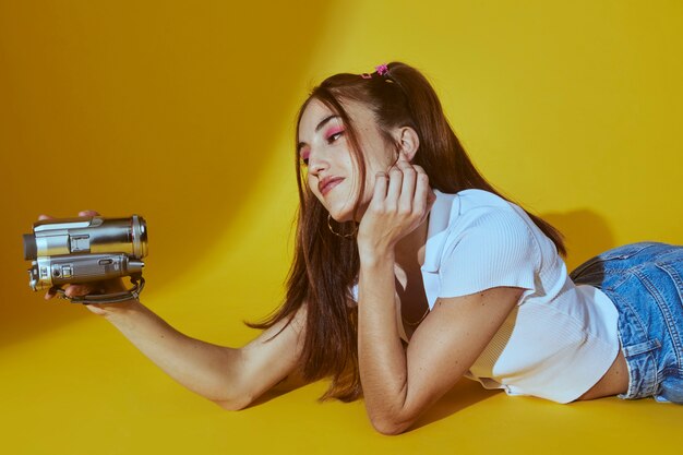 Portrait de jeune femme dans le style de la mode des années 2000 posant avec caméra