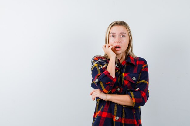 Portrait de jeune femme debout dans la peur pose en chemise à carreaux et à la vue de face renforcée