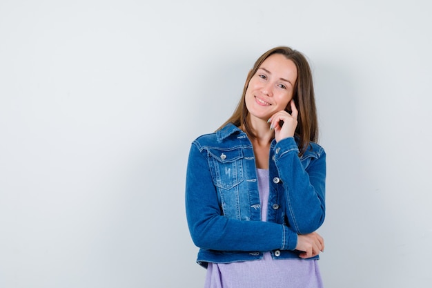 Portrait de jeune femme debout en pensant pose en t-shirt, veste et à la vue de face joyeuse