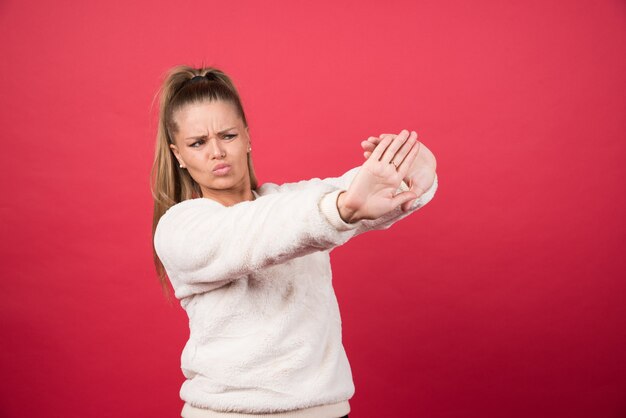 Portrait d'une jeune femme debout et posant sur un mur rouge