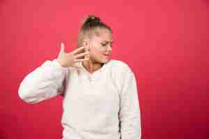 Photo gratuite portrait d'une jeune femme debout et posant sur un mur rouge