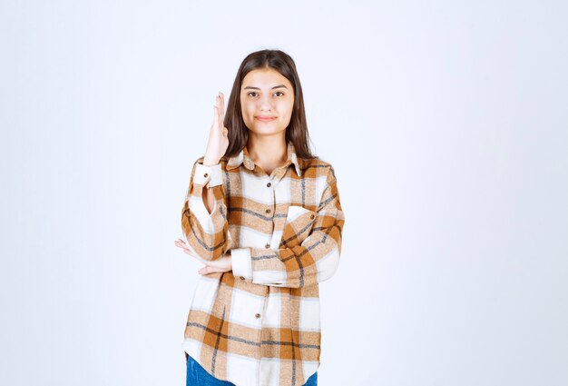 Portrait de jeune femme debout et prête à répondre sur un mur blanc.