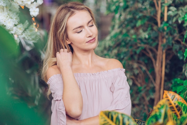 Portrait de jeune femme décontractée debout parmi les plantes vertes