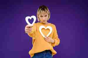 Photo gratuite portrait de jeune femme avec décor coeurs sur mur violet