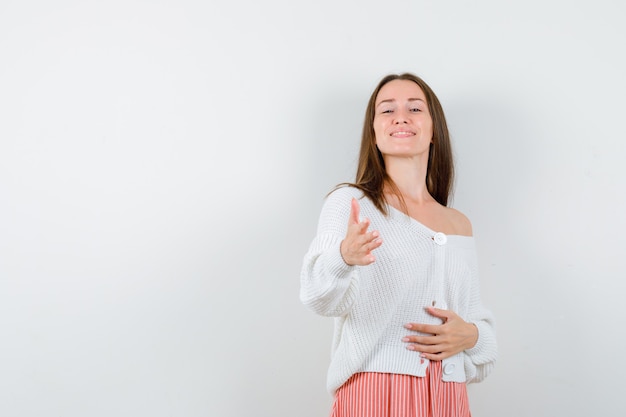 Portrait de jeune femme donnant la main pour salutation en cardigan et jupe isolé