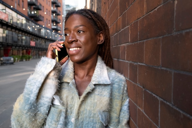 Portrait de jeune femme avec des dreadlocks afro parlant sur smartphone à l'extérieur