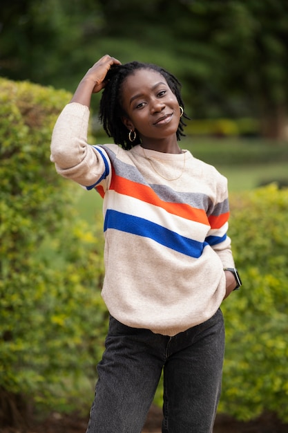 Portrait de jeune femme avec des dreadlocks afro posant à l'extérieur