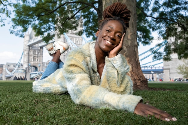 Portrait de jeune femme avec des dreadlocks afro posant sur l'herbe dans la ville