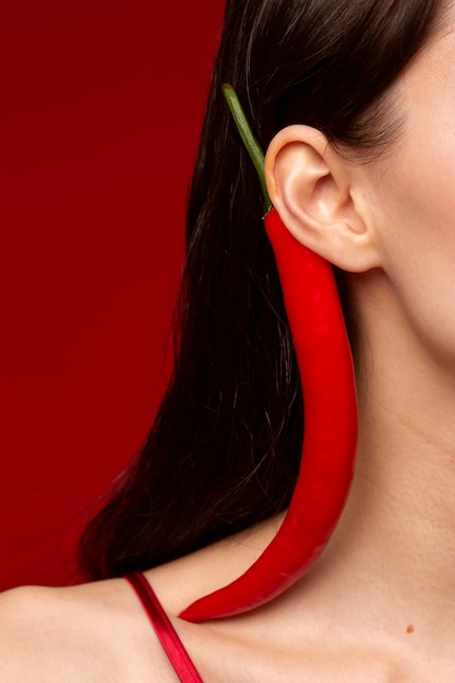 Portrait de jeune femme avec du piment rouge derrière son oreille
