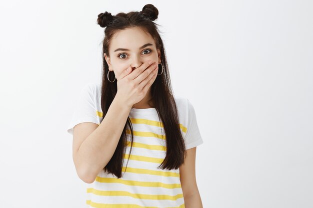 Portrait de jeune femme élégante choquée posant contre le mur blanc