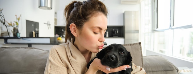 Photo gratuite portrait d'une jeune femme embrassant son chien mignon câlinant son ami à quatre pattes sur un canapé en passant du temps