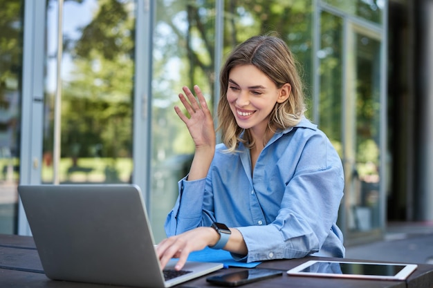 Photo gratuite portrait de jeune femme étudiante chat vidéo en ligne à partir d'un café en plein air femme d'affaires ayant une réunion o