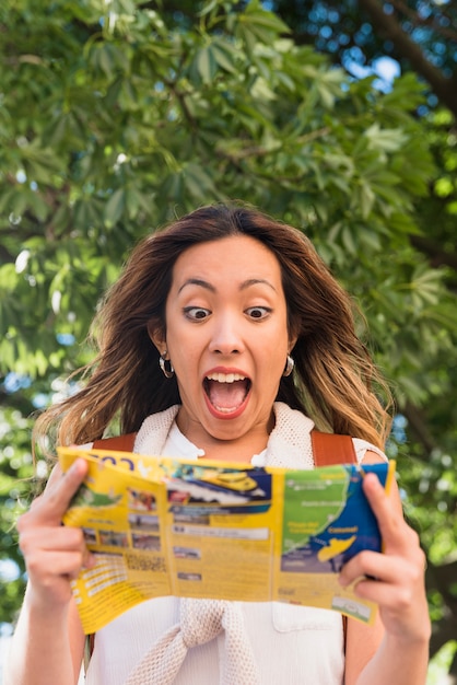 Photo gratuite portrait d'une jeune femme excitée en regardant une carte touristique