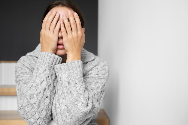 Photo gratuite portrait de jeune femme avec une faible estime de soi assise dans les escaliers à la maison