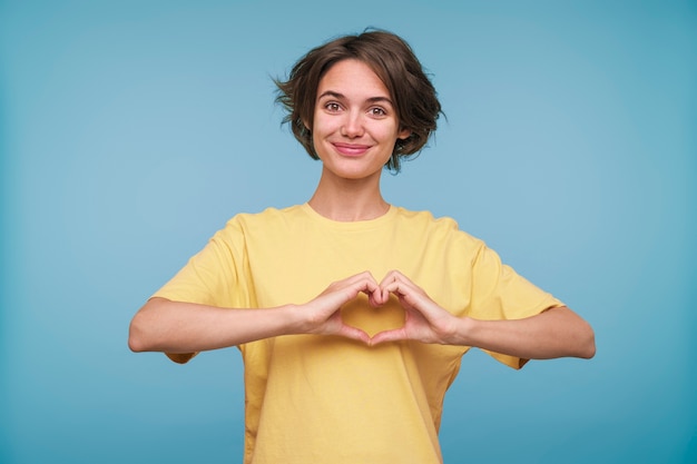 Portrait d'une jeune femme faisant un coeur avec ses mains