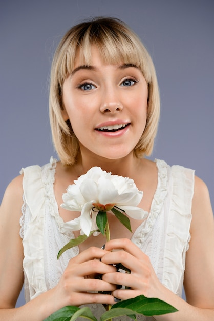 Portrait de jeune femme avec fleur sur mur gris