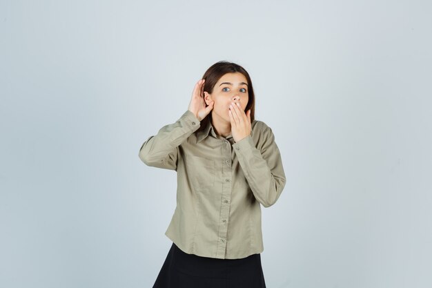 Portrait de jeune femme gardant la main sur la bouche tout en entendant le secret