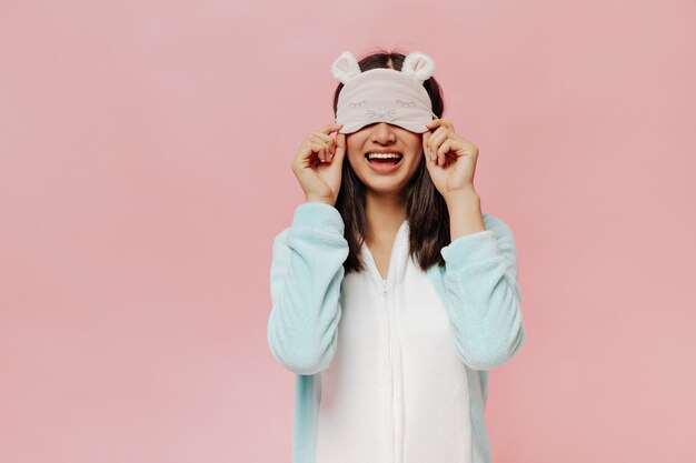 Photo gratuite portrait d'une jeune femme heureuse met un masque de sommeil mignon