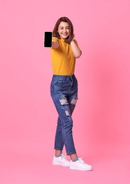 Portrait de jeune femme heureuse montrant au téléphone mobile à écran blanc sur rose.