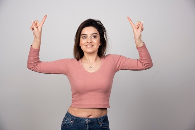 Portrait d'une jeune femme heureuse pointant les doigts vers le haut.