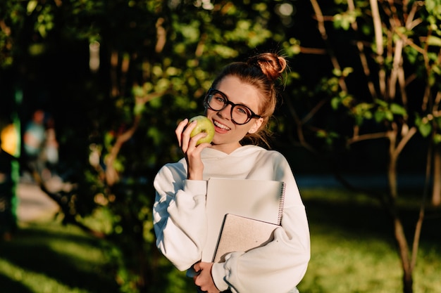 Portrait d'une jeune femme heureuse de rire avec des cheveux collectés marchant en contre-jour