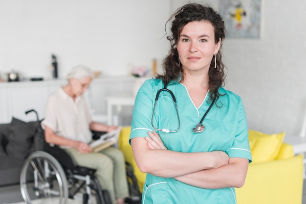 Portrait de jeune femme infirmière debout devant une femme senior assis sur une chaise roulante
