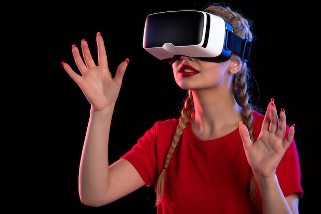 Portrait de jeune femme jouant avec enthousiasme à la réalité virtuelle sur le mur sombre