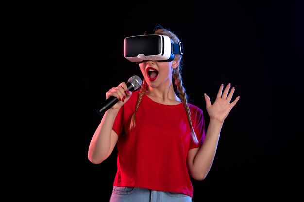 Portrait de jeune femme jouant à la réalité virtuelle et chantant sur un jeu visuel de musique sombre