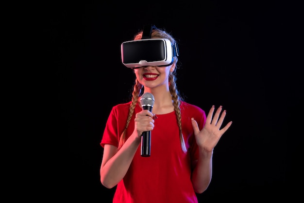 Portrait de jeune femme jouant à la réalité virtuelle et chantant sur un visuel échographique sombre