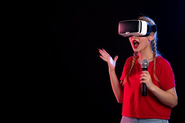 Portrait de jeune femme jouant à la réalité virtuelle et chantant sur un visuel de jeu de musique sombre