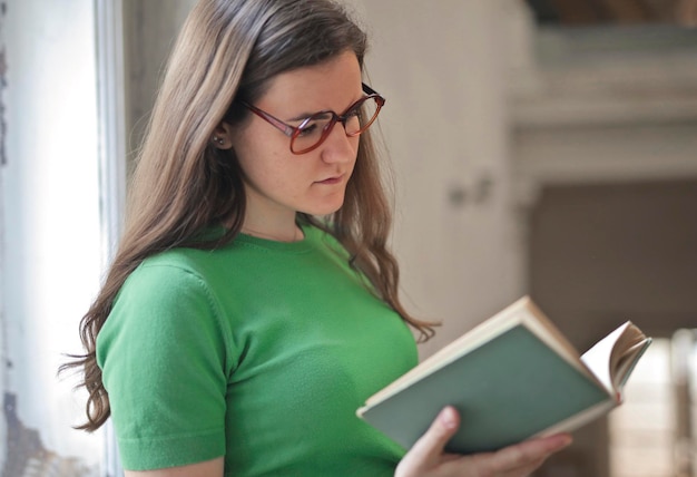 portrait de jeune femme avec des lunettes en lisant un livre