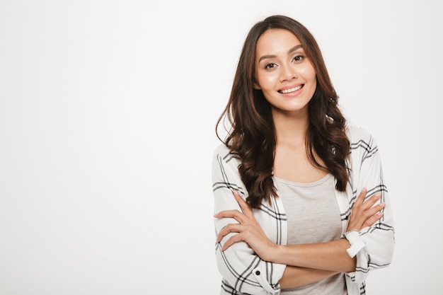 Portrait de jeune femme avec un magnifique sourire debout avec les bras croisés isolé, sur blanc