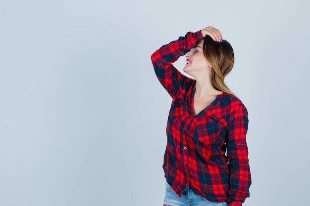 Portrait De Jeune Femme Avec La Main Sur La Tête En Chemise à Carreaux Et à La Vue De Face Oublieux