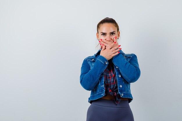 Portrait de jeune femme avec les mains sur la bouche en chemise, veste et à la vue de face effrayée