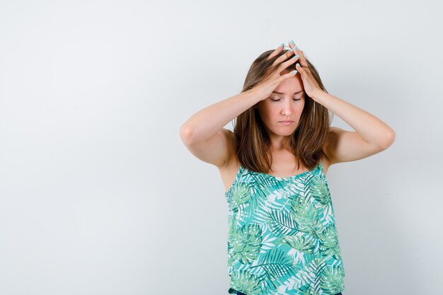 Portrait de jeune femme avec les mains sur la tête en blouse et à la vue de face épuisé