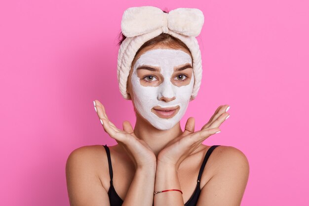 Portrait de jeune femme avec masque d'argile du visage, a un bandeau blanc autour de la tête