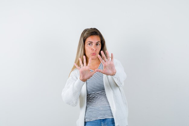 Portrait de jeune femme montrant le geste d'arrêt en t-shirt, veste et à la vue de face effrayée