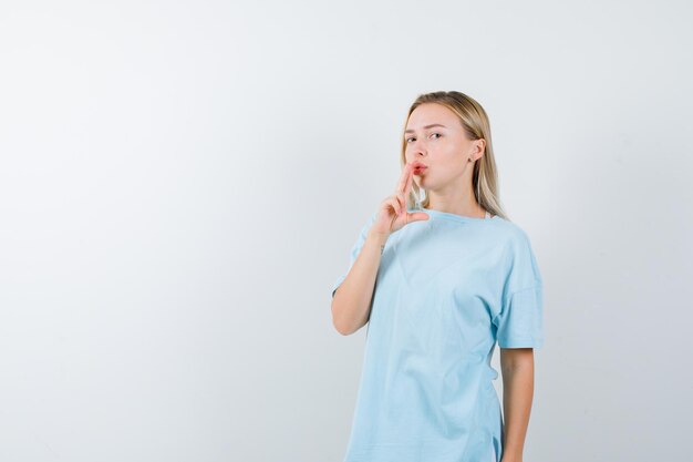 Portrait de jeune femme montrant le geste du pistolet sur la bouche en t-shirt isolé