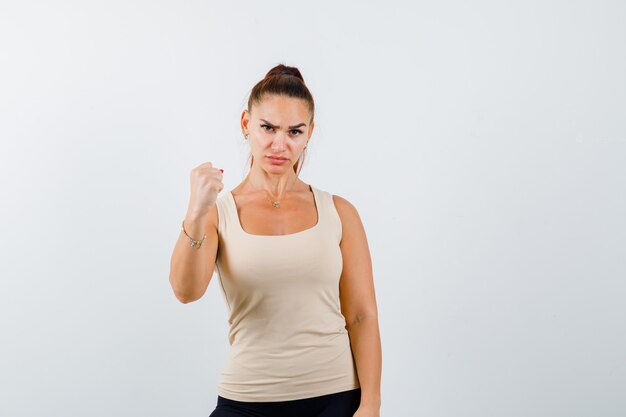 Portrait de jeune femme montrant le geste gagnant en débardeur et à la vue de face sérieuse