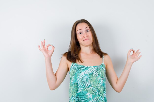 Portrait de jeune femme montrant un geste ok en blouse et à la vue de face confiante