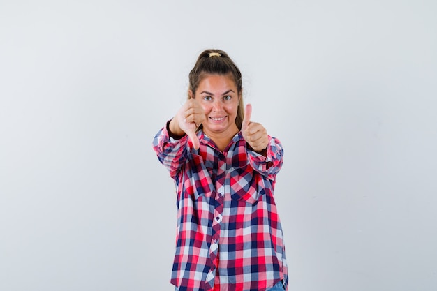 Portrait De Jeune Femme Montrant Les Pouces De Haut En Bas En Chemise Décontractée Et à La Vue De Face Jolly