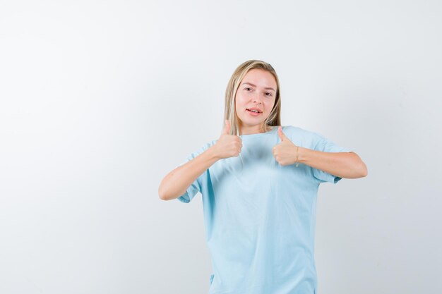 Portrait de jeune femme montrant les pouces vers le haut en t-shirt et à la recherche de gai isolé