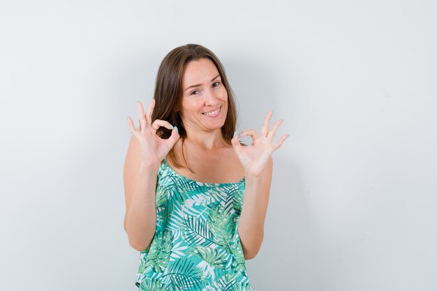 Portrait de jeune femme montrant un signe ok et à la vue de face joyeuse