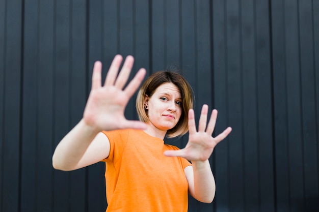 Portrait, de, a, jeune femme, montrer, arrêt, geste, contre, mur noir