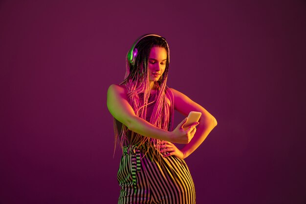 Portrait de jeune femme sur mur rose avec un casque