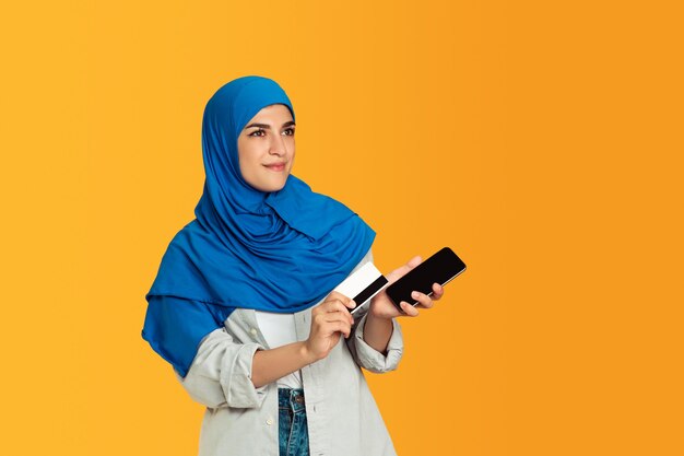 Portrait de jeune femme musulmane sur mur jaune