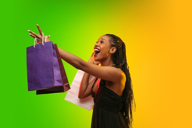 Portrait de jeune femme en néon avec des sacs à provisions, vendredi noir