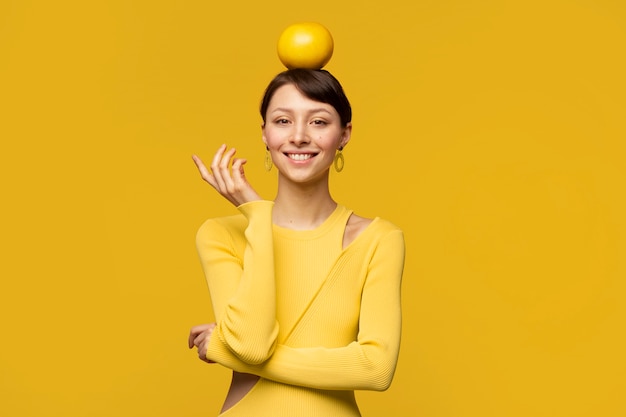 Portrait de jeune femme avec un pamplemousse sur la tête