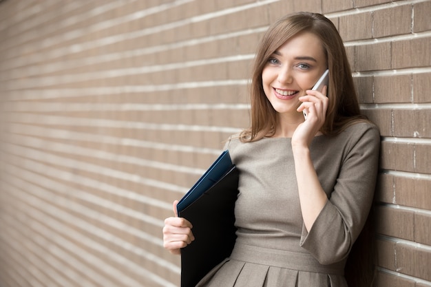 Portrait de jeune femme parlant au téléphone et regardant la caméra dans la rue