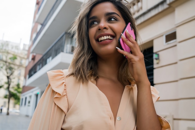 Portrait de jeune femme parlant au téléphone tout en se tenant à l'extérieur dans la rue